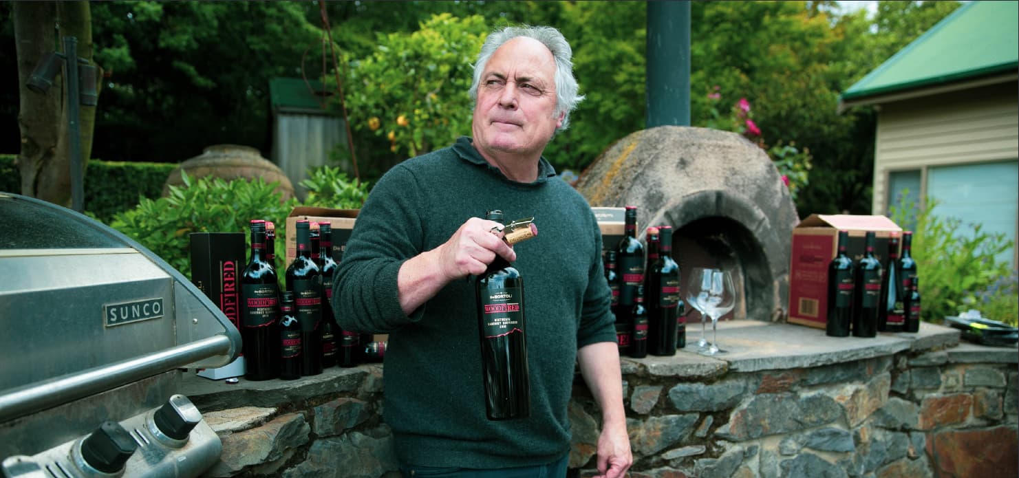Steve Webber ingarden, holding bottle of Woodfired